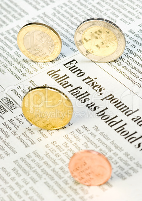 Euromünzen rollen über Zeitungsseite