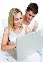 Couple using a laptop in bed