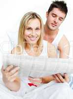 Woman and man reading newspaper in bed