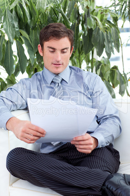 Businessman reading papers on a sofa