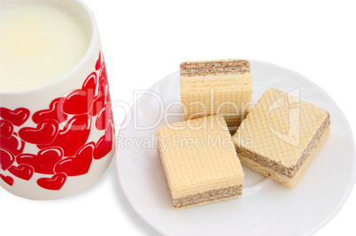 Ceramic mug with milk and a white saucer with wafers