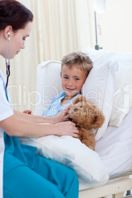 Female doctor listening to a child chest and a teddy bear
