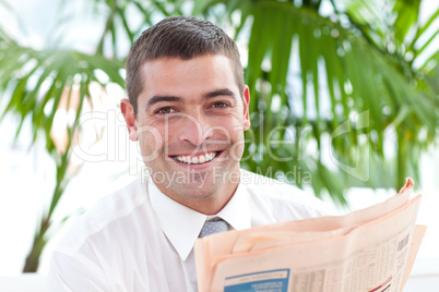 Portrait of a businessman reading a newspaper in workplace