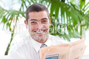 Portrait of a businessman reading a newspaper in workplace