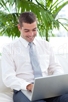 Happy businessman using a laptop on sofa