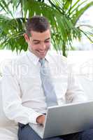 Happy businessman using a laptop on sofa