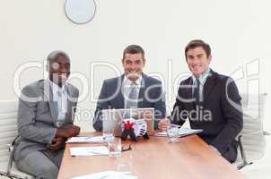 Three businessmen in a meeting smiling