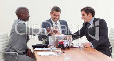 Happy businessmen in a meeting looking at a laptop