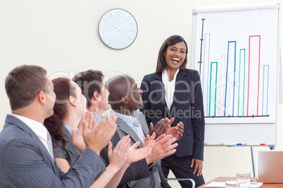 Business people applauding her colleague in a meeting