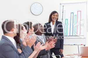 Business people applauding her colleague in a meeting