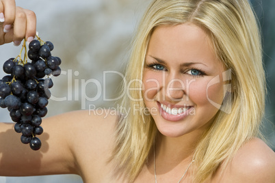 Beautiful Young Blond Woman Eating A Bunch of Grapes