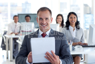 Smiling manager writing notes in a call center