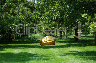 Man-made pumpkin in the middle of apple-trees.