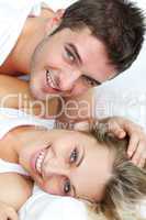 Smiling lovers lying in bed