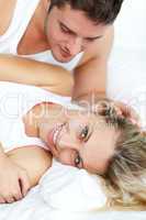 Attractive man looking at his girlfrined in bed