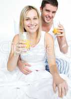 Boyfriend and girlfriend drinking orange juice in bed