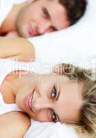 Beautiful smiling woman lying in bed with her boyfriend