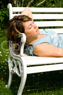 Frau liegt auf einer Gartenbank