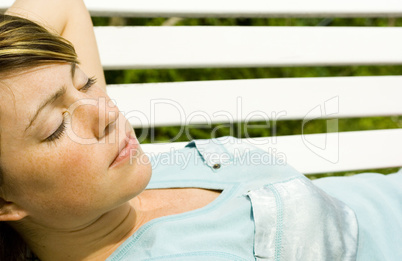 Frau liegt auf einer Gartenbank