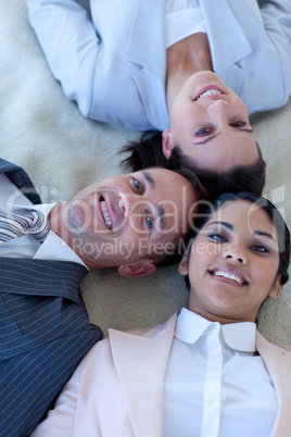 Business team on floor with heads together smiling