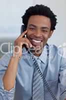 Portrait of smiling Afro-American businessman on phone in office