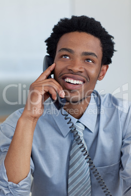 Attractive smiling Afro-American businessman on phone in office