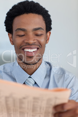 Smiling Afro-American businessman reading a newspaper