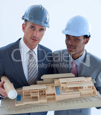 Close-up of architects holding a model house in office