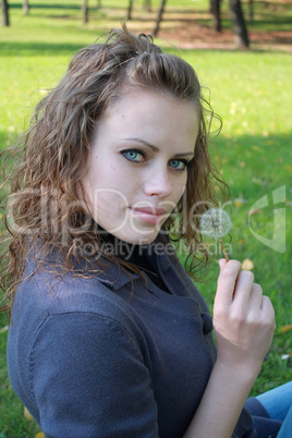 beautiful girl holds a dandelion in a hand