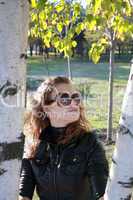 young girl costs near a tree