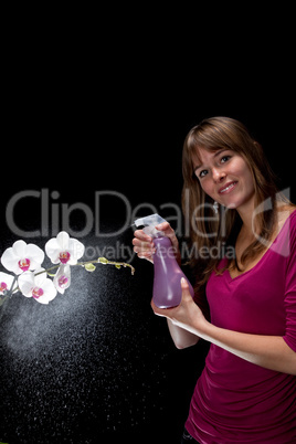 hübsche junge Frau sprüht Wasser auf eine Orchidee