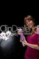 hübsche junge Frau sprüht Wasser auf eine Orchidee