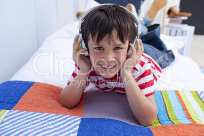 Smiling boy listening to music in bed with headphones on