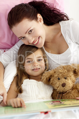 Portrait of mother and daughter reading in bed