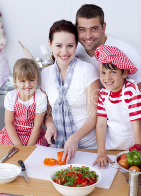 Young family cutting vegetables in kitchen