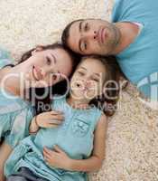 Portrait of parents and daughter on floor with heads together
