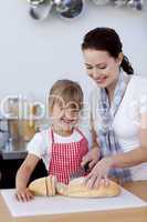 Mother teaching daughter how to cut bread