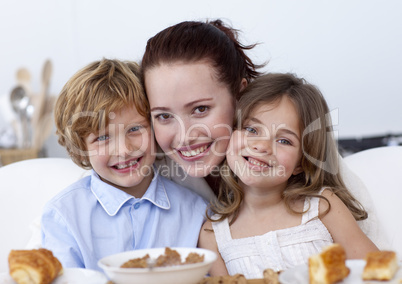 Smiling children having breakfast with their mother