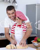 Smiling father and son cutting bread