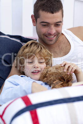 Portrait of father and son reading a book in bed