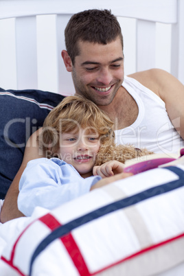 Dad and kid reading a book in bed