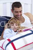 Dad and kid reading a book in bed