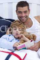 Father and son reading a book in bed