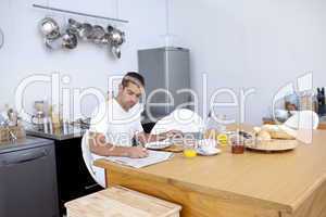 Busy man having breakfast and working in kitchen