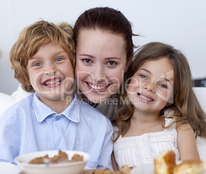 Portrait of children having breakfast with their mother