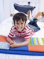Portrait of boy on headphones listening to music in bed