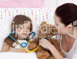 Sick daughter playing with a stethoscope with her mother