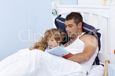 Father and son reading a book in bed