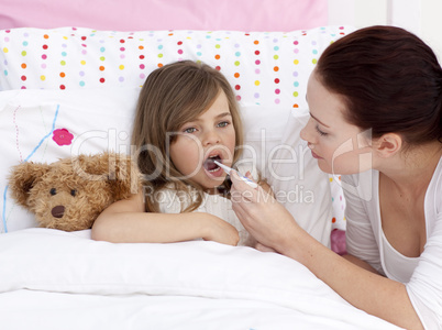 Mother taking her daughter's temperature with a thermometer