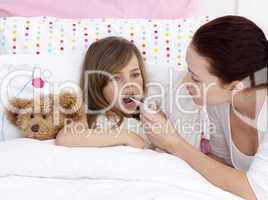 Mother taking her daughter's temperature with a thermometer